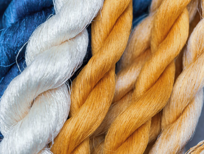 A series of different colored threads starting at the left with a deep blue then white and then a golden yellow
