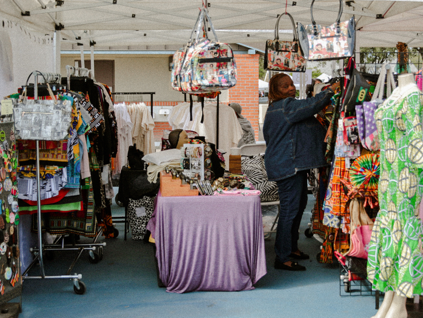 A women at a stand where different handmade dresses, bags and other accessories are being sold