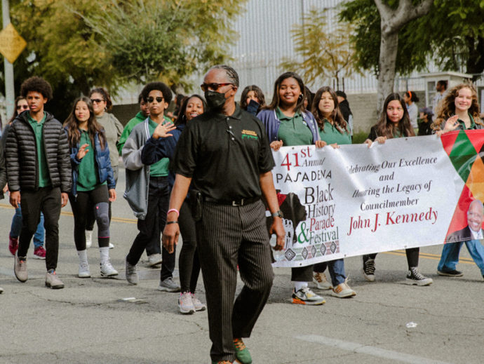 A group of students holding up a banner that says 41st annual Pasadena Black HIsoty Parade & Festival Celebrating Our Excellence and Honoring the Legacy of Councilmember John J. Kennedy